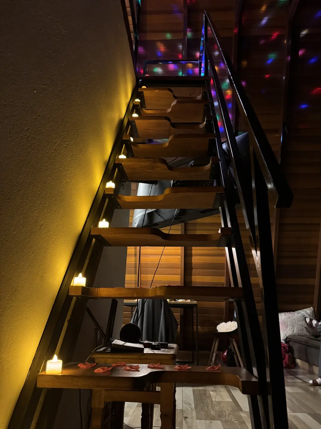 Escada de madeira da cabana com velas de LED nos degraus e as luzes do globo giratório projetadas no teto